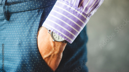 Close-up of Male Hand in Pants Pocket with Elegant Wristwatch. Caucasian Businessman in Striped Shirt Wearing Stylish Dress Watch. Fashion and Punctuality Concept