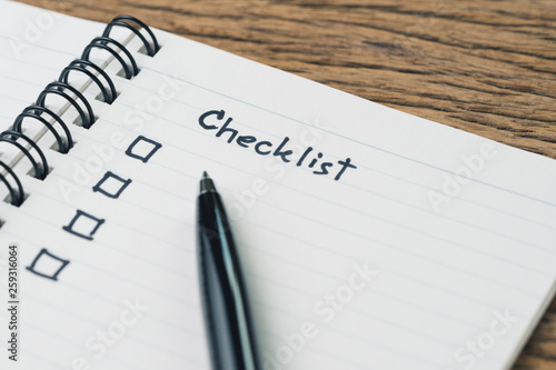Checklist, to do list, prioritize or reminder for project plan, handwriting headline the word Checklist with black marker pen and check box on small notepad on wood table