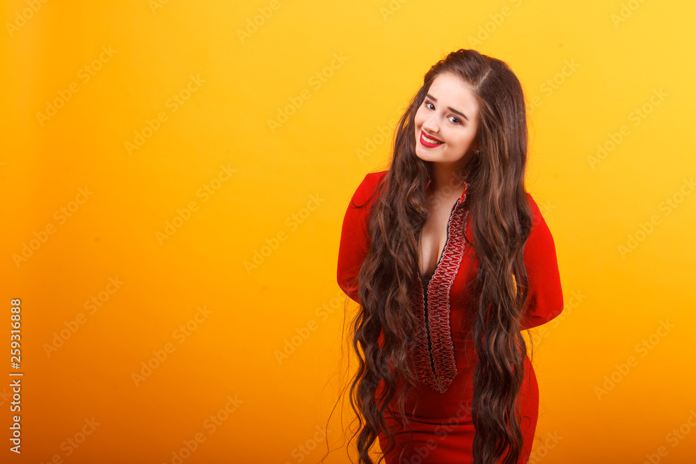 Beautiful young woman in red mini dress. Studio shot on yellow background. Beautiful young woman in red mini dress. Studio shot on yellow background.
