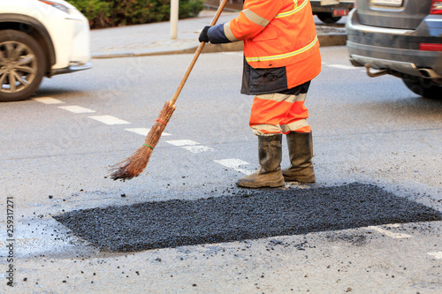 A road worker collects fresh asphalt with a panicle on the part of the road being repaired.