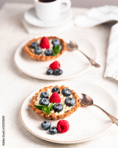 homemade tartlets with blueberries and raspberries on a light marble backdrop, overexposed
