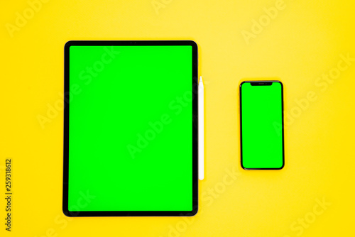 new tablet on a Yellow background with a keyboard and pen, and green screen top view