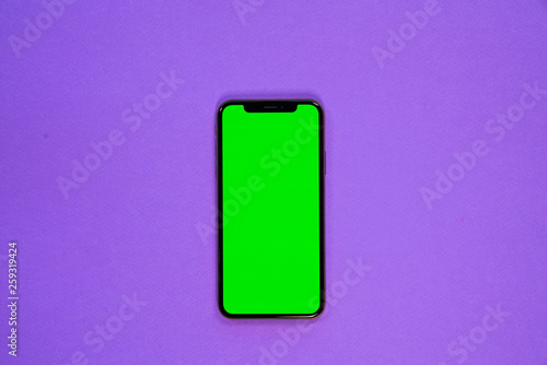 iPhone XS, smartphone, green screen on Violet background top view