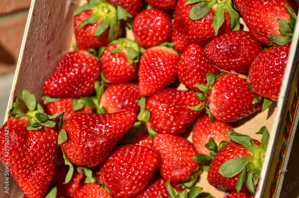 A fruit box full of bright red strawberries, blurred background. A fruit box full of bright red strawberries, blurred background.