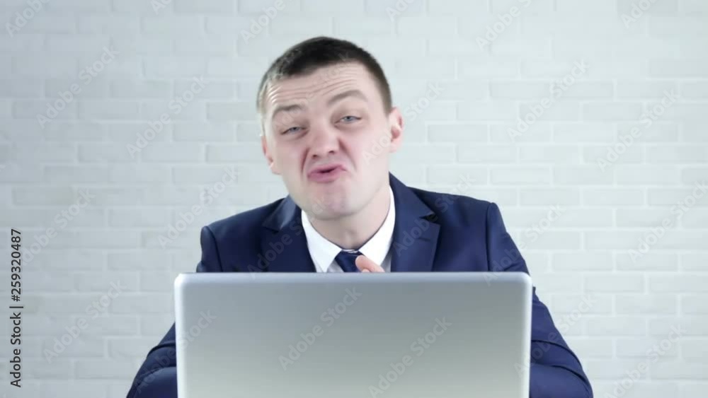 A young worker makes funny faces.Businessman grimacing A young worker makes funny faces.Businessman grimacing
