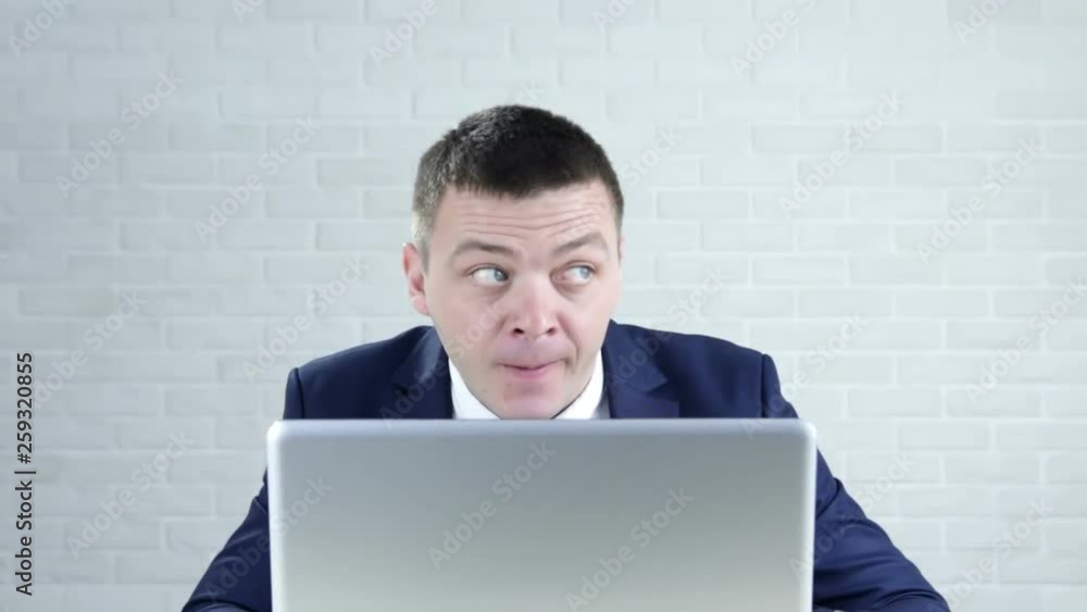 Businessman with his laptop sitting in the office showing a sign of closing mouth and silence gesture Businessman with his laptop sitting in the office showing a sign of closing mouth and silence gesture