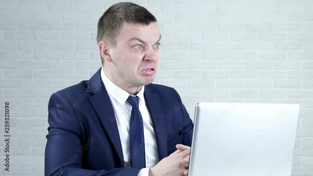 A young worker makes funny faces while the boss does not see. A young worker makes funny faces while the boss does not see.