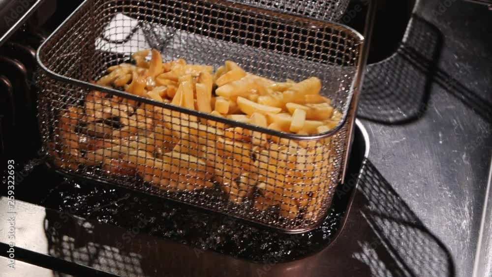 Shaking off oil from french fries preparing to be served. Dripping in a