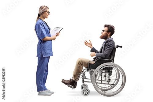 Young female nurse talking to a bearded man in a wheelchair