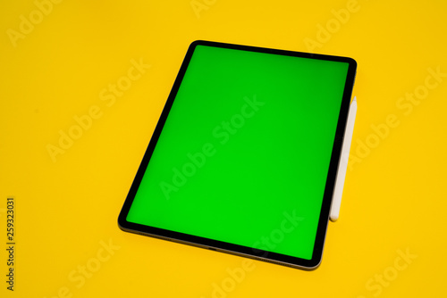 new iPad, tablet on a Yellow background with a keyboard and pen, and green screen top view