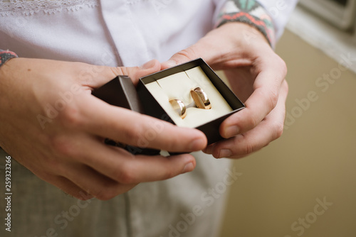 Man in white shirt holds little brown gift-box with wedding rings. close up