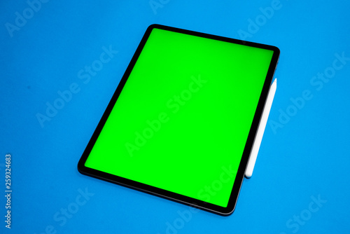 new iPad, tablet on a Blue background with and pen, and green screen