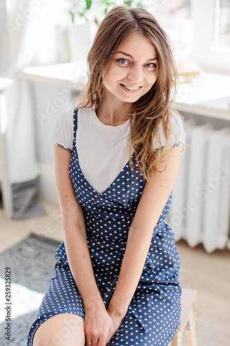 Fashionable woman in a blue sundress with polka dots posing in the Studio.