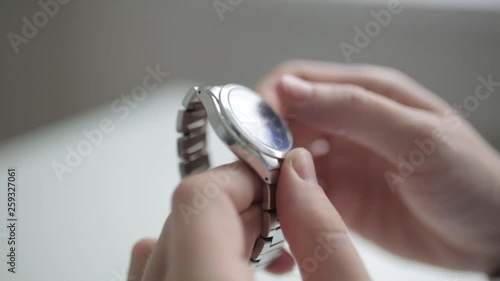  Hands in macro shooting and steel watch. Setting the metal clock on time.