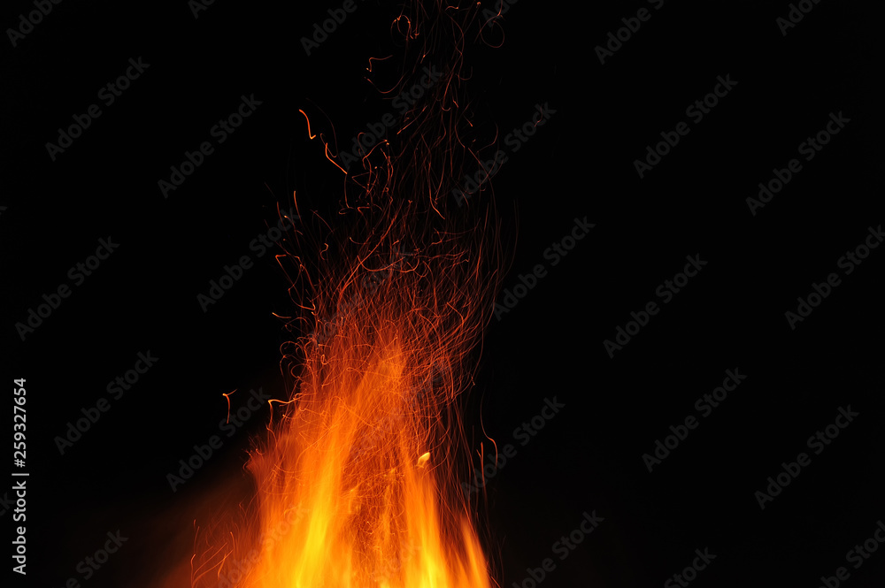 Flame of a burning fire with sparks in the night on a black background. Close-up Flame of a burning fire with sparks in the night on a black background. Close-up