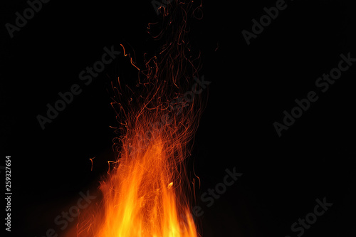 Flame of a burning fire with sparks in the night on a black background. Close-up