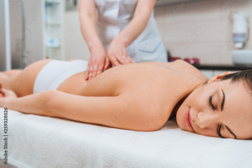 Partial view of masseur doing back massage to girl on massage table Partial view of masseur doing back massage to girl on massage table