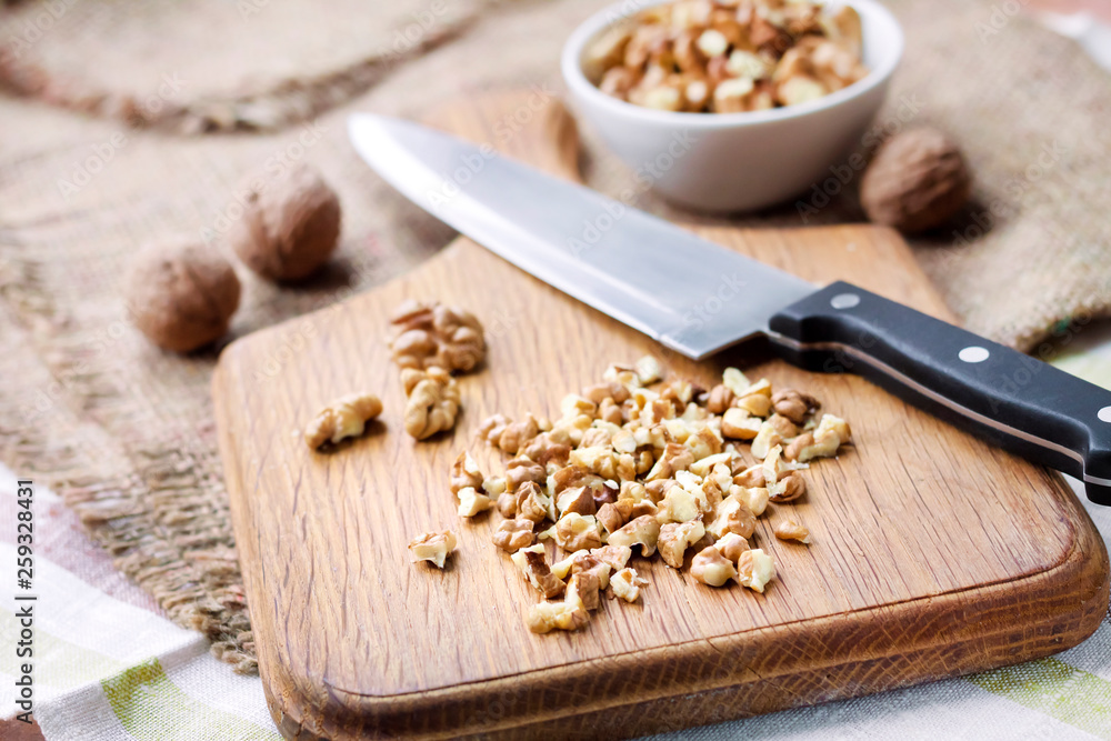 Fototapeta premium Chopped walnuts on wooden cutting board