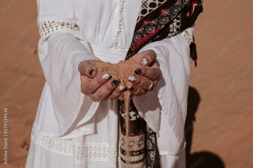 Close-up of female hand releasing dropping sand. Sand flowing through the hands in desert 