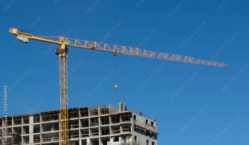 building and cranes under construction against blue sky building and cranes under construction against blue sky