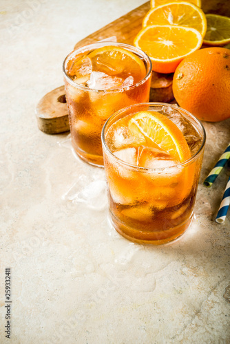 Cold summer cocktail, Iced coffee dink with orange slices, stone table copy space