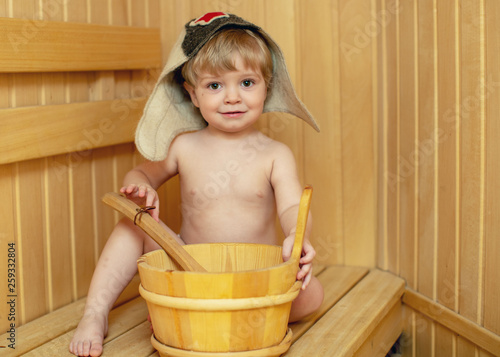 Beauty, healthcare. baby Boy relaxing in the sauna Toddler with broom and hat in russian sauna or bath