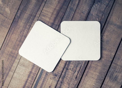 Two blank square beer coasters on vintage wooden background. Flat lay.