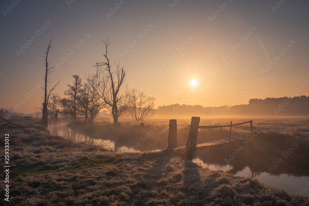 Sunrise over the wooden bridge in valley of the Jeziorka river near Piaseczno, Masovia, Poland