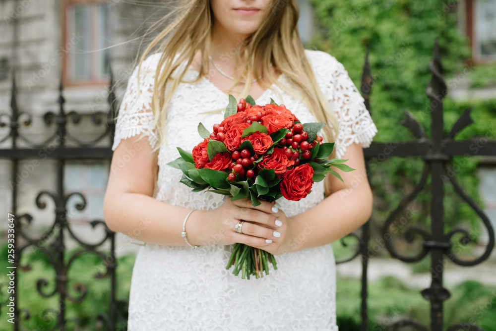 Hands of the bride hold a bouquet of red flowers Hands of the bride hold a bouquet of red flowers