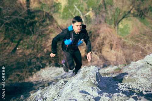 Man running in a park or forest against trees background.