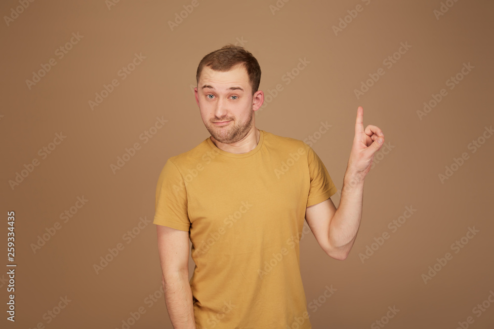 young man in yellow shirt shows a finger up like have idea