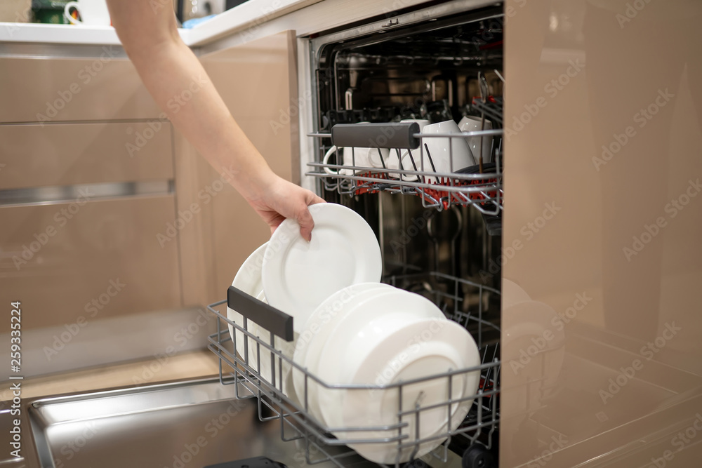 Woman holding in hand plate and getting out or putting in it in kithen or dishwasher shelf. Woman holding in hand plate and getting out or putting in it in kithen or dishwasher shelf.