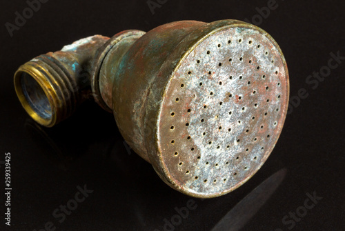 close up of an old tarnished antique brass shower head isolated on white