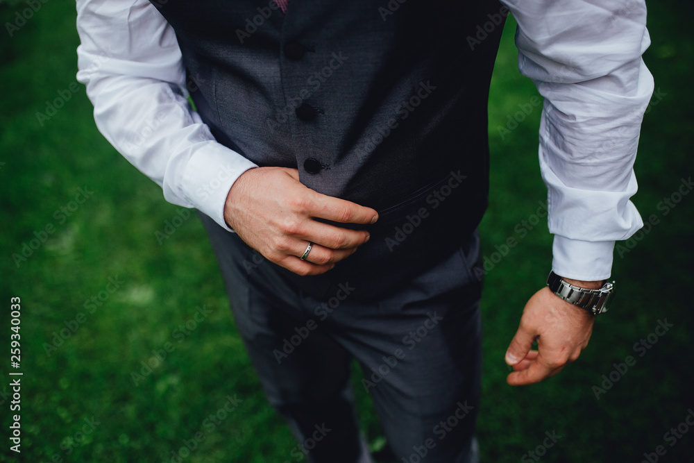 Detailed close up photo of a handsome groom in a grey suit with a vest.
