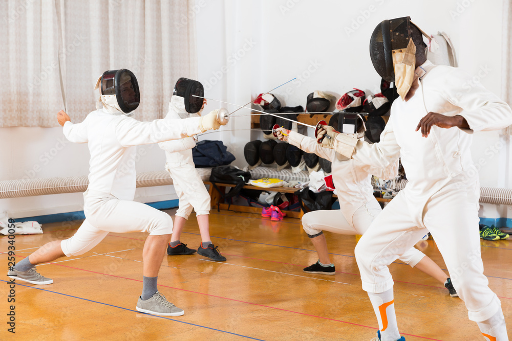 Cheerful group  practicing fencing techniques