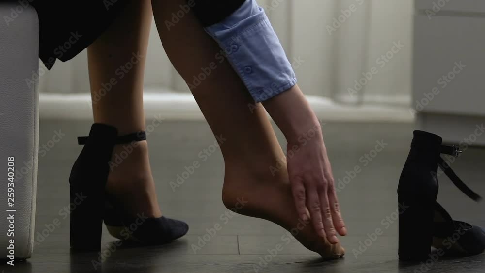 Young woman taking off shoes and massaging legs, tired after all day walk Young woman taking off shoes and massaging legs, tired after all day walk