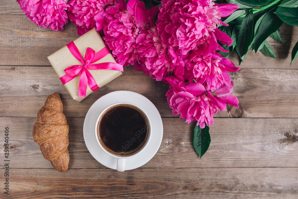 A cup of coffee and pink peony pattern on wooden background . . Valentines Day and Mother's Day background . A cup of coffee and pink peony pattern on wooden background . . Valentines Day and Mother's Day background .