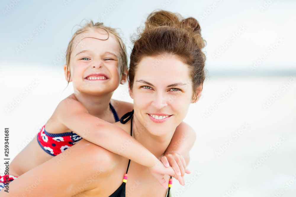 Portrait of happy mother and little daughter on sunny beach on Maldives at summer vacation Portrait of happy mother and little daughter on sunny beach on Maldives at summer vacation
