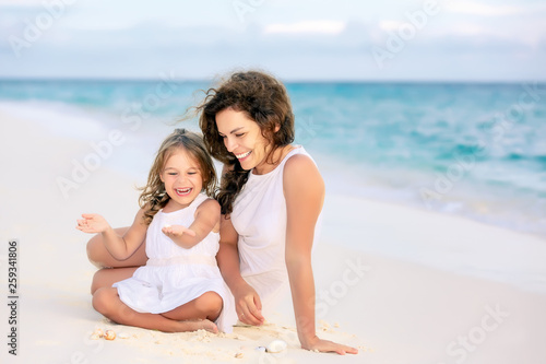 Mother with little daughter playing on ocean beach  Maldives