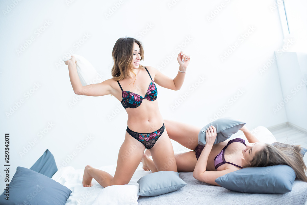 Two beautiful girls in lingerie have fun in a pillow fight. Stock Photo |  Adobe Stock