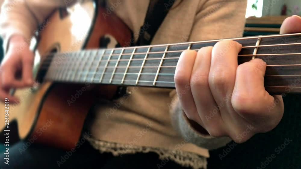 female hands play the guitar. A happy carefree young girl plays the guitar female hands play the guitar. A happy carefree young girl plays the guitar