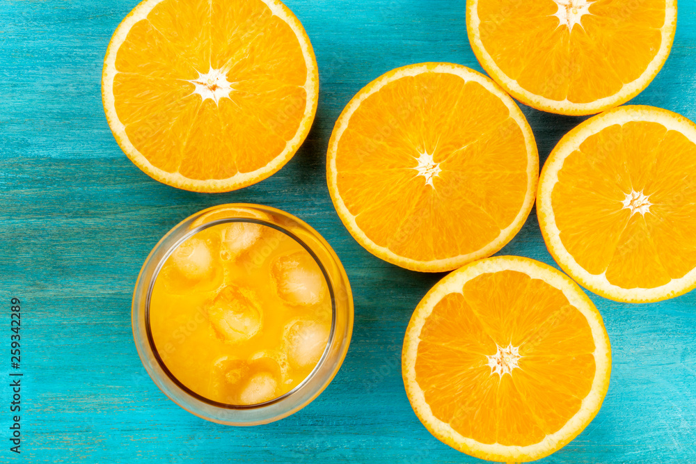 A closeup photo of a glass of fresh orange juice with orange halves, shot from the top on a vibrant blue background A closeup photo of a glass of fresh orange juice with orange halves, shot from the top on a vibrant blue background