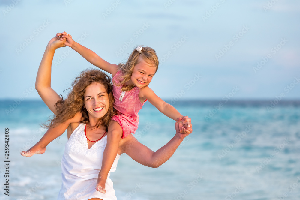 Portrait of happy mother and little daughter on sunny beach on Maldives at summer vacation Portrait of happy mother and little daughter on sunny beach on Maldives at summer vacation