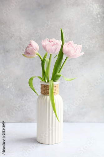Pink tulips in vase on grey background