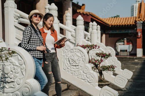 group of female friends travelers walking down stairs on stone fence in front of Taihe Gate Beijing Imperial Palace China. happy smiling asian women visit chinese history monument with guide book. photo