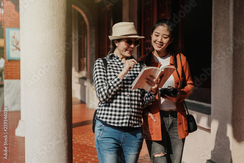 Fotografie two happy cheerful smiling asian girl travelers walking in corridor at Confucian temple