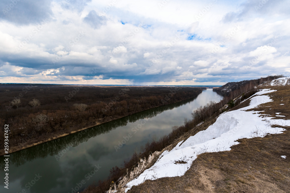 wide river in spring. snow on the river Bank. overcast sky
