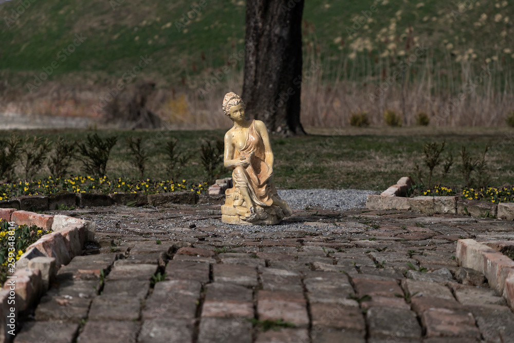 Fototapeta premium Woman statue in a garden illuminated with afternoon light
