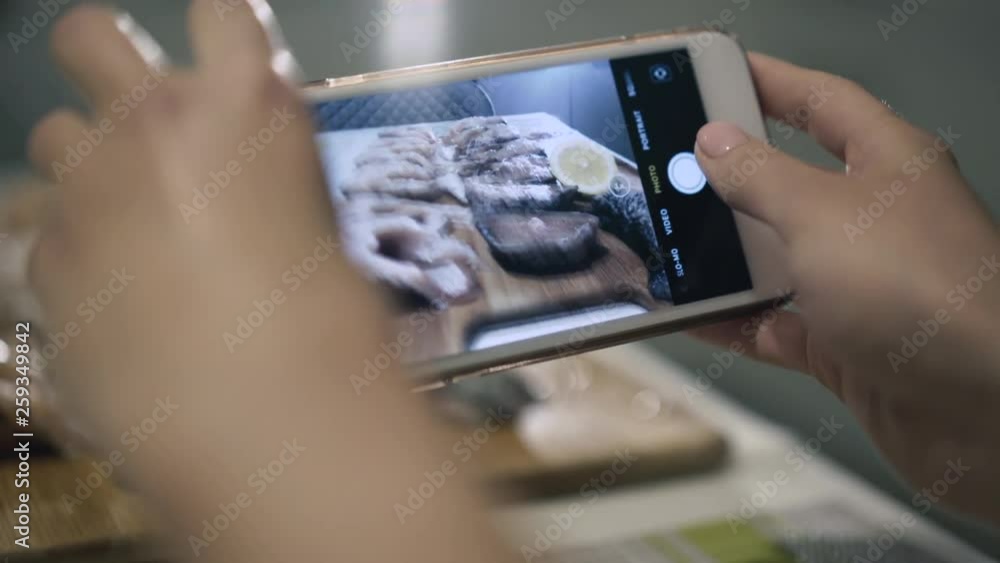 Female hands takes photos with fish set on phone camera
