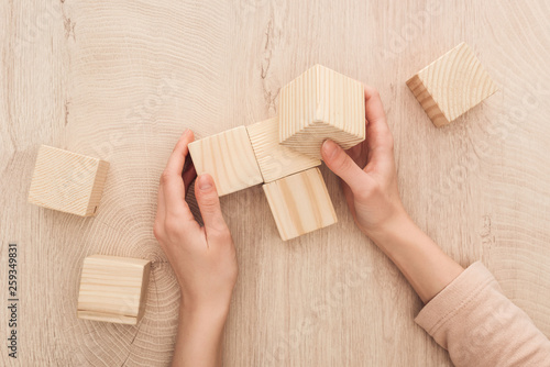partial view of female hands near blank wooden cubes